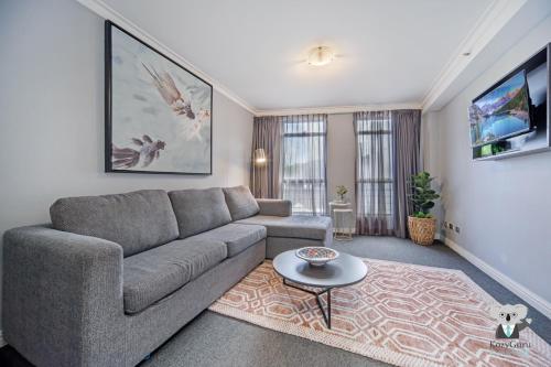 a living room with a couch and a table at KozyGuru | Sydney CBD | Sunny City 2 Bed Apt in Sydney