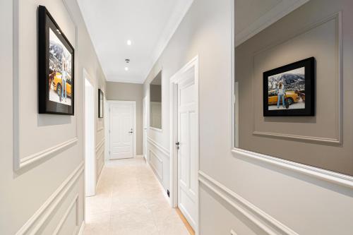 a hallway with white walls and pictures on the walls at Sofiesgate Lux Apartment in Oslo