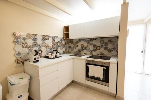 a small kitchen with white cabinets and a stove at Antica Dimora Storica La Finestra Sul Campanile in Matera