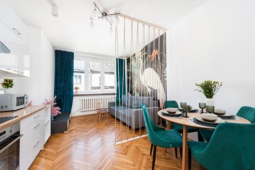 una cucina e una sala da pranzo con tavolo e sedie verdi di Vistula River Apartment a Cracovia
