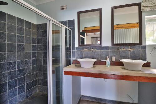 a bathroom with two sinks and two mirrors at Aloe Arbour Self-catering cottages in White River