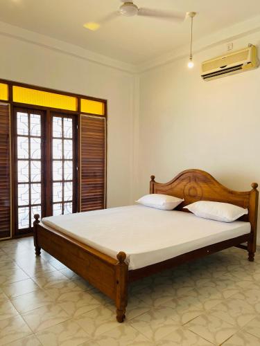 a bedroom with a wooden bed in a room at Serendib Villa Mirissa in Mirissa