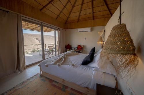 a bedroom with a bed and a large window at Le Bédouin agafay in Marrakech