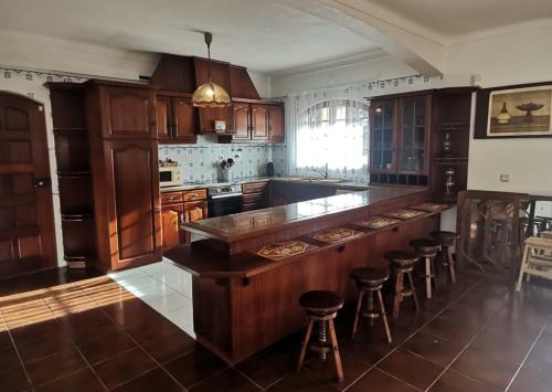 a large kitchen with wooden cabinets and bar stools at CASA COM ARTE - Hospitality & Rural Impact in Vermelho