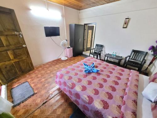 a bedroom with a pink bed with a blue bow on it at Abode Me Me Ai Haven in Cherrapunji