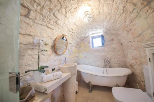 Baño de piedra con bañera y lavamanos en Trulli Dimore - Trulli della Lama, en Castellana Grotte