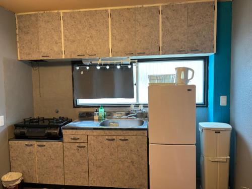 a small kitchen with a sink and a refrigerator at 777 Takamatsu Guest House in Takamatsu