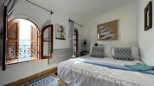 a bedroom with a bed and an open window at RIAD OASIS D'ASILAH in Asilah