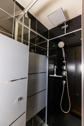 une douche dans une salle de bain aux murs noirs dans l'établissement La Longère Forézienne, à Sainte-Agathe-la-Bouteresse