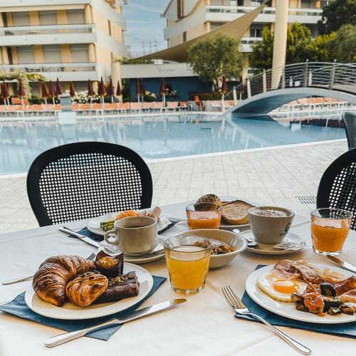 - une table avec des assiettes de nourriture pour le petit-déjeuner à côté de la piscine dans l'établissement Villaggio Planetarium Resort, à Bibione