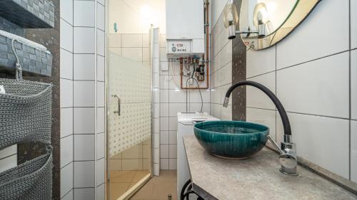 a bathroom with a sink with a green bowl on a counter at Kútvölgy Vendégház in Vác