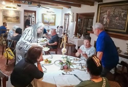 a group of people sitting around a table in a restaurant at Coach House Hotel & Spa Tzaneen in Tzaneen