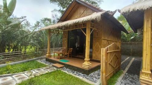 a small hut with a deck in a garden at Pondok Sapta Sallaca in Selat