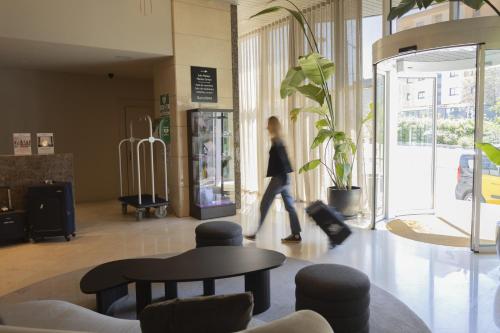 a woman walking through a lobby with a person walking through a building at Best Western Premier CMC Girona in Girona