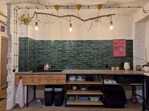 a kitchen with a counter and green brick wall at Mākslas studija Koknesē in Koknese