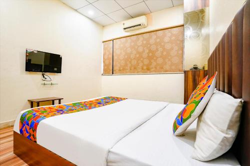 a bedroom with a bed and a tv and a bed sidx sidx sidx at FabHotel Gokuldham in Surat