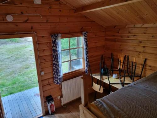 um quarto com uma cama e uma janela num chalé de madeira em Ofvansjö Gård , Enkel stuga för övernattning på ett fd militärområde em Sandviken
