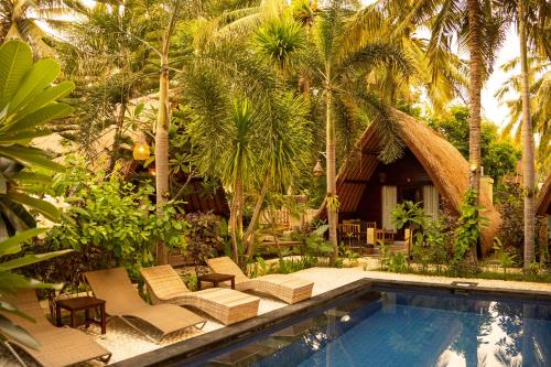 a resort with a swimming pool and palm trees at Selvática in Gili Islands