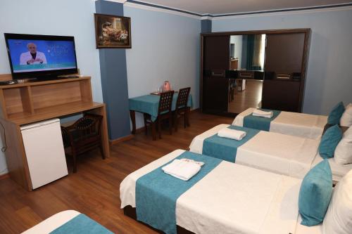 a hotel room with three beds and a flat screen tv at Adana Saray Hotel in Adana
