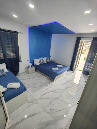 a bedroom with two beds and a blue wall at Vesuvius Dream in Boscotrecase
