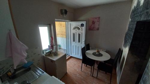 uma cozinha com uma mesa e cadeiras e uma porta branca em Apartman Ivona em Ovcar Banja