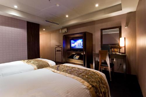 a hotel room with two beds and a television at H.M.Hotel in Hsinchu City
