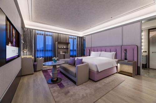 1 dormitorio con cama, sofá y TV en Grand Mercure Hangzhou Zhejiang University en Hangzhou