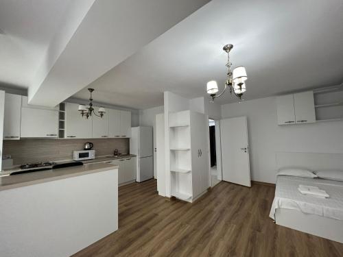 a white kitchen with white cabinets and a bed in a room at Tatarasi Wolf Apartaments and Studios Iasi in Iaşi