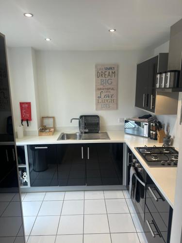 uma cozinha com armários pretos e um lavatório em Luxury Furnished 2 Bed Northampton apartment with Balcony near NN5 stadium em Northampton