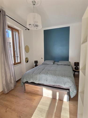 une chambre avec un lit avec un mur bleu dans l'établissement Appartement de charme avec balcon au pied des commerces, à Béziers