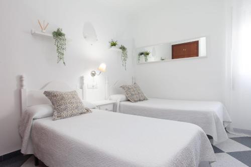 2 łóżka w pokoju z białymi ścianami w obiekcie Hostal Restaurante La Giralda w mieście Rota