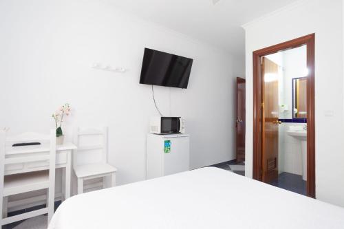 a bedroom with a bed and a desk and a television at Hostal Restaurante La Giralda in Rota