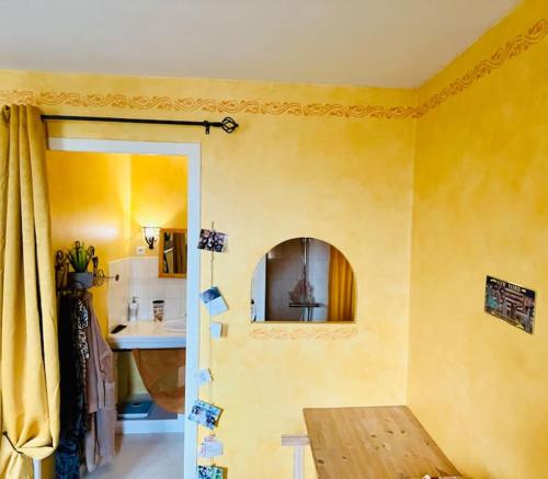 Cette chambre jaune comprend une table et un miroir. dans l'établissement Villa de charme au milieu des vignes, à Saint-Aubin-de-Blaye