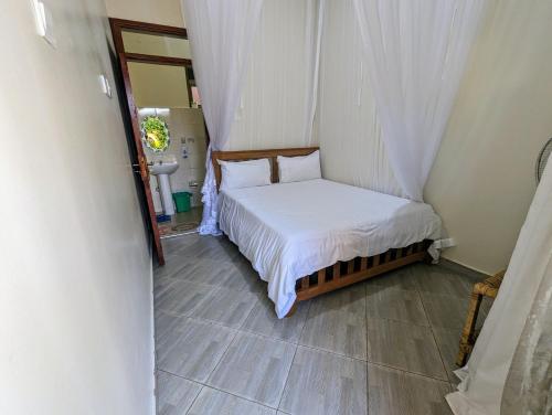 a small bedroom with a bed and a mirror at Oslo Gardens Bed & Breakfast in Entebbe