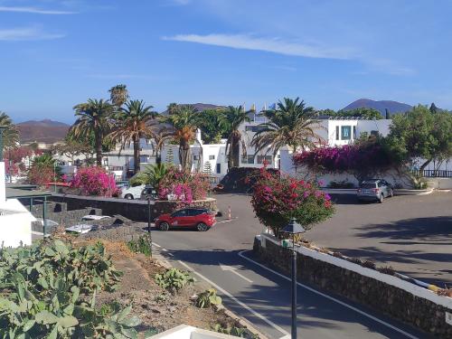 een parkeerplaats met palmbomen en een rode auto bij Casa Gara in Yaiza