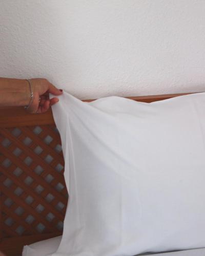 a person is putting a pillow on a bed at Vegas Residence - Adults Only in Albufeira