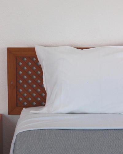 a bed with a white pillow and a wooden headboard at Vegas Residence - Adults Only in Albufeira