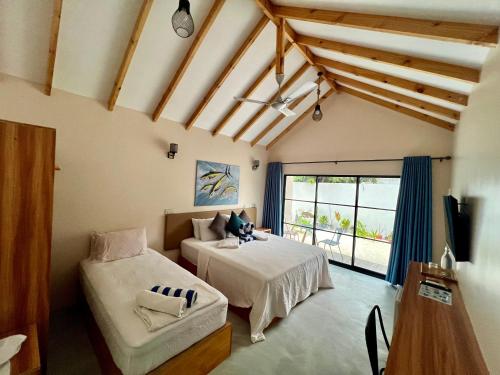 a room with two beds and a chair in it at Manta Stay Thoddoo, Maldives in Thoddoo