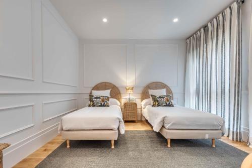 two beds in a room with white walls and windows at Apartamento Canalejas Place en Madrid in Madrid