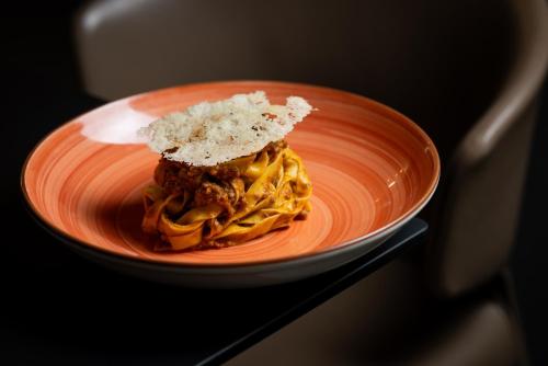 an orange plate with pasta and cheese on it at UNA Hotels Bologna Fiera in Bologna