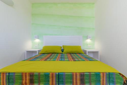 a bed with a yellow blanket and two green pillows at Cava Li Santi Residence in Nardò