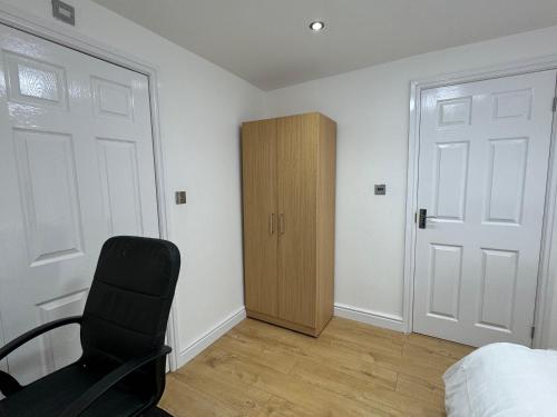 a bedroom with a black chair and a closet at Room with en-suite facilities in Ashford