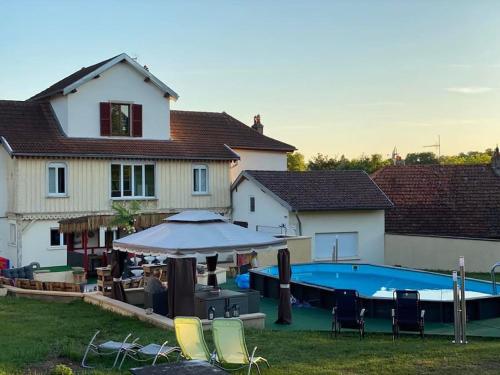 ein Haus mit einem Pool mit Stühlen und einem Sonnenschirm in der Unterkunft Maison Hôtes Villa Sainte Barbe in Mirecourt