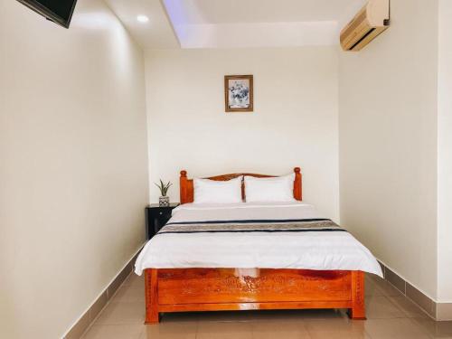1 dormitorio con cama de madera en una habitación blanca en Nhà Nghỉ Rạng Đông, en Kon Tum