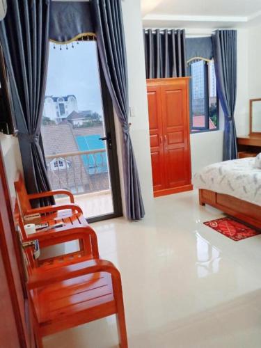 1 dormitorio con 2 sillas, 1 cama y 1 ventana en Nhà Nghỉ Rạng Đông, en Kon Tum