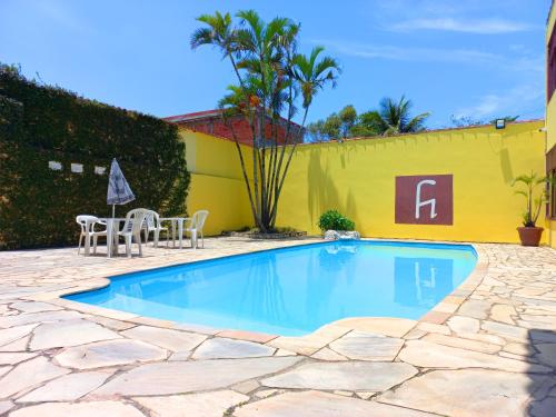 a swimming pool with chairs and a yellow wall at Guarujá H Pousada in Guarujá