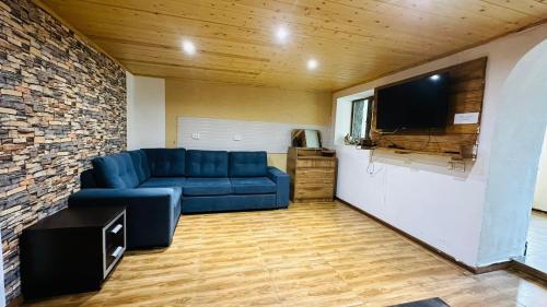 ein Wohnzimmer mit einem blauen Sofa und einem Flachbild-TV in der Unterkunft House in Mestia Mood of silence svaneti in Lagami
