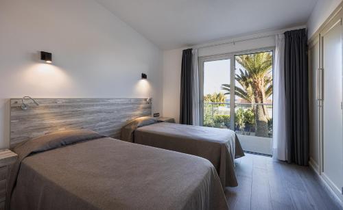 普拉亞戴爾雷安格萊斯的住宿－Smartr Maspalomas Corinto，酒店客房设有两张床和大窗户。