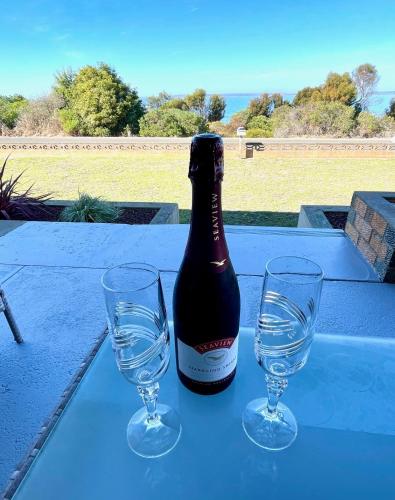 a bottle of wine and two glasses on a table at Kangaroo Island Seabright House in Kingscote