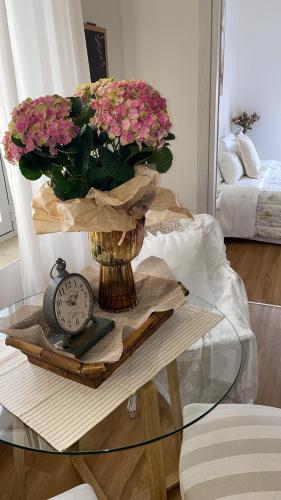 a table with a vase with flowers and a clock at La ROMANTICA VERONA in Verona